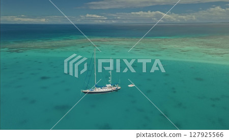 A large sailing vessel with multiple masts is anchored in crystal-clear turquoise waters. 127925566