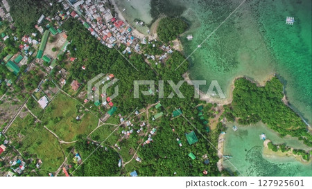 Stunning aerial drone footage captures the idyllic beauty of Malapascua Island in the Philippines, showcasing the vibrant coastline, traditional outrigger boats, and lush tropical vegetation 127925601