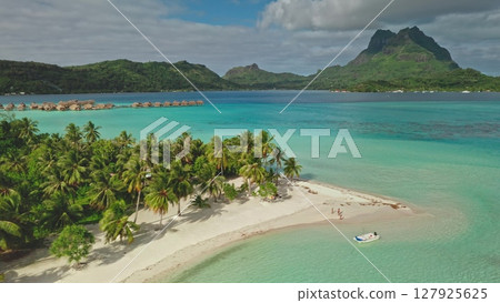 Tropical motu, small islet, in Bora Bora, French Polynesia, with some tourists walking on the beach and overwater bungalows visible in the distance. Enjoy vacation travel adventure nature. Aerial view Tropical motu, small islet, in Bora Bora, French Polynesia, with some tourists walking on the beach and overwater bungalows visible in the distance. Enjoy vacation travel adventure nature. Aerial view 127925625