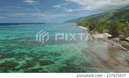 Aerial view of Tahiti island coastline showing crystal clear turquoise water gently washing a beautiful tropical beach with lush vegetation and a small white church in the background Aerial view of Tahiti island coastline showing crystal clear turquoise water gently washing a beautiful tropical beach with lush vegetation and a small white church in the background 127925637