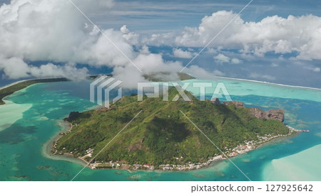 Aerial drone flight high in clouds show breathtaking beauty of Maupiti island in French Polynesia, green mountain, turquoise lagoon, coral reefs under cloudy sky. Remote wild nature travel background Aerial drone flight high in clouds show breathtaking beauty of Maupiti island in French Polynesia, green mountain, turquoise lagoon, coral reefs under cloudy sky. Remote wild nature travel background 127925642