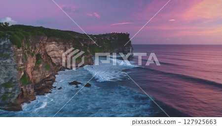 Uluwatu Temple standing on high cliff overlooking the beautiful Pantai Dreamland Beach with colorful sky during sunset in Bali, Indonesia, creating stunning scenery Uluwatu Temple standing on high cliff overlooking the beautiful Pantai Dreamland Beach with colorful sky during sunset in Bali, Indonesia, creating stunning scenery 127925663