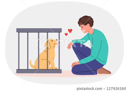 Man wants to adopt dog from shelter and become guardian for pet, standing near smiling puppy in cage 127926160