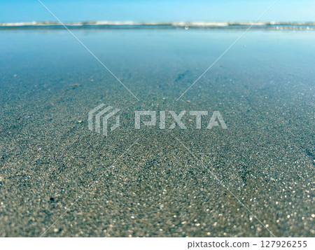 Sparkling sand on a shallow in the Ligurian Sea. Panorama of the seashore with a close-up of the sand. Sparkling sand on a shallow in the Ligurian Sea. Panorama of the seashore with a close-up of the sand. 127926255