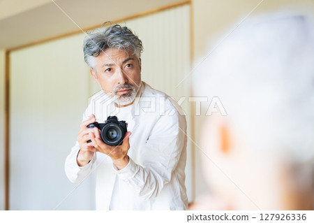 Senior male photographer photographing a female model 127926336