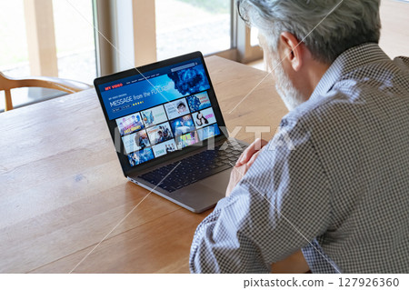 老人在筆記型電腦上觀看視訊串流服務 老人在筆記型電腦上觀看視訊串流服務 127926360