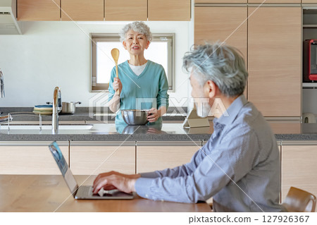 Senior woman getting angry at her husband who works from home Senior woman getting angry at her husband who works from home 127926367