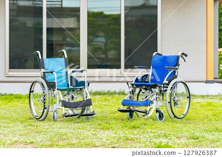 Two wheelchairs in front of a house Two wheelchairs in front of a house 127926387