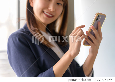 Woman operating a smartphone Woman operating a smartphone 127926466