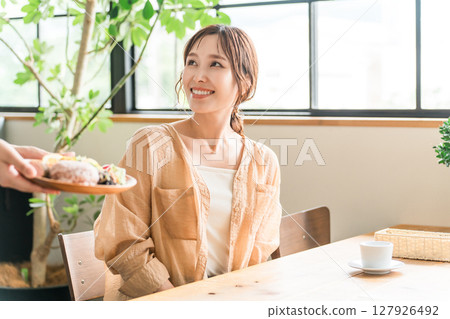 一名店員和一名女顧客在咖啡館提供一盤午餐 一名店員和一名女顧客在咖啡館提供一盤午餐 127926492