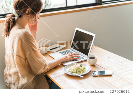 一位女士在咖啡館吃午餐時進行遠距工作 一位女士在咖啡館吃午餐時進行遠距工作 127926611