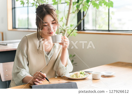 A woman working remotely while drinking coffee in a cafe 127926612
