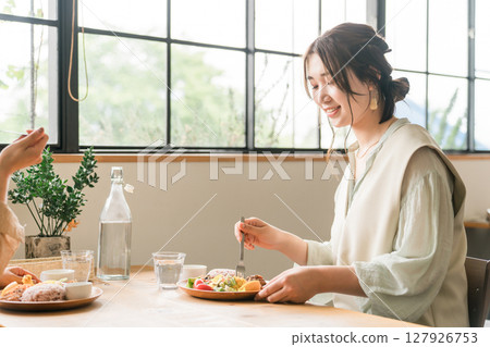 A woman eating a delicious lunch with her female friends (girls' gathering) A woman eating a delicious lunch with her female friends (girls' gathering) 127926753