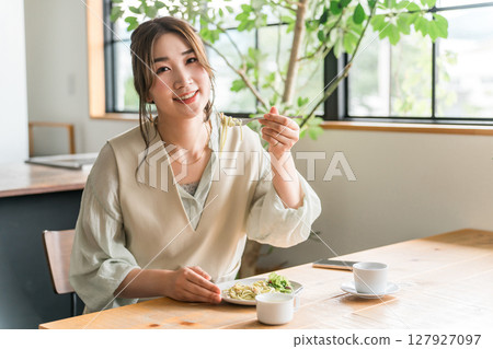 一位年輕的亞洲女性在咖啡館吃義大利麵作為午餐 127927097