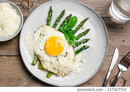 Fried egg with green asparagus and grated parmesan cheese for breakfast 127927591