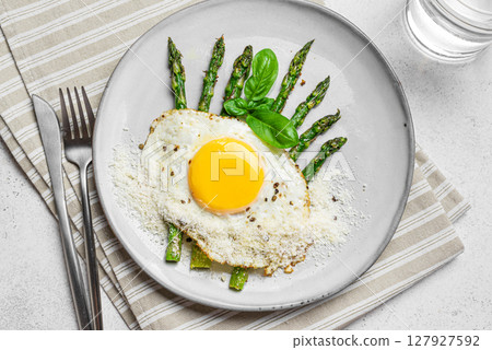 Fried egg with green asparagus and grated parmesan cheese, healthy breakfast 127927592