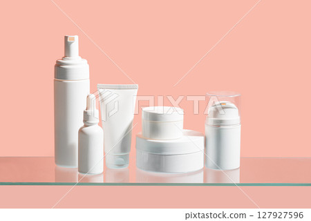 White cosmetic containers on glass shelf 127927596