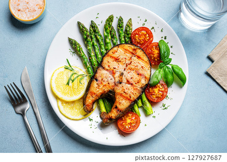 Grilled salmon steak with green asparagus, tomatoes and lemon slices 127927687
