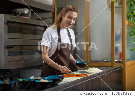 Woman shapes dough in kitchen working carefully preparing homemade pizza 127928388