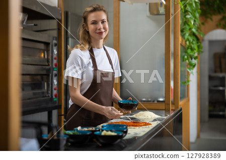 Man helps woman spread sauce pizza kitchen collaborating happily 127928389