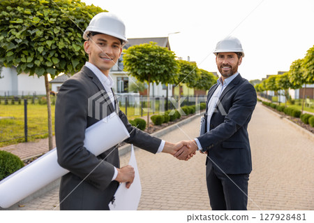 Engineers shaking hands with blueprints Engineers shaking hands with blueprints 127928481