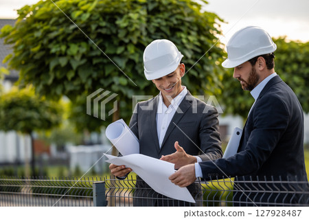 Construction team analyzing plans in green area 127928487