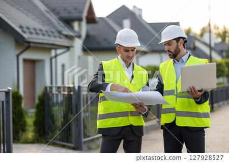 Construction team inspecting site with blueprints 127928527