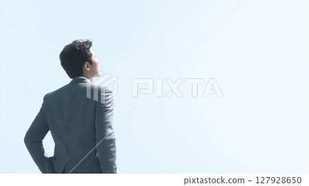 Businessman looking up at the sky, bust shot, copy space on the right 127928650