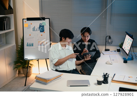 Colleagues discussing data and strategies late at night 127928901