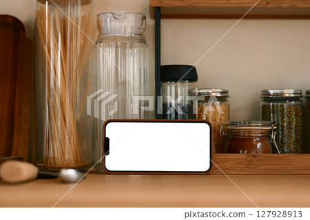 Smartphone with blank screen in horizontal position on a wooden kitchen counter Smartphone with blank screen in horizontal position on a wooden kitchen counter 127928913