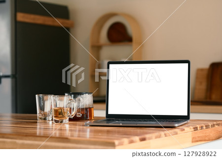 Laptop with blank screen on kitchen counter with tea cups and a teapot beside Laptop with blank screen on kitchen counter with tea cups and a teapot beside 127928922