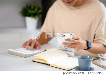 Close up shot of man managing household expenses with receipts and calculator Close up shot of man managing household expenses with receipts and calculator 127928956