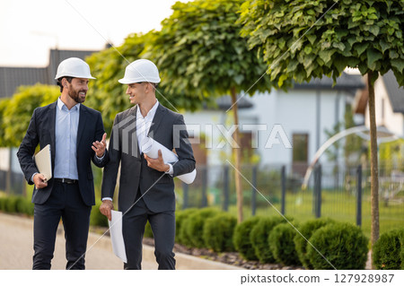 Construction team analyzing plans in green area 127928987