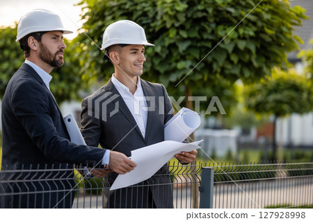 Builders discussing plans with technology outdoors Builders discussing plans with technology outdoors 127928998