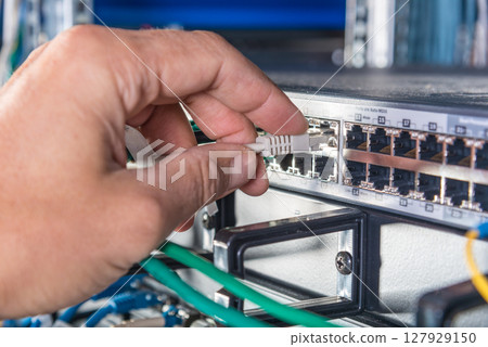 hand of engineer plugging in ethernet cable into server switch p 127929150