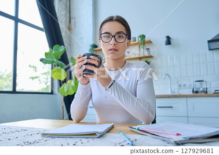 Webcam portrait serious female student teenager, sitting at home at the table 127929681