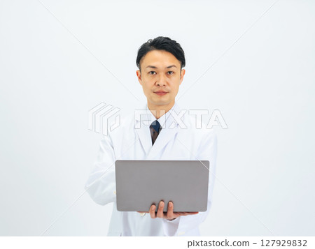 Middle-aged male doctor/scientist in a white coat using a laptop 127929832