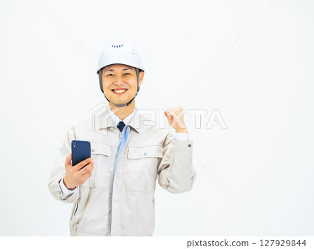A middle-aged man wearing work clothes posing with a smartphone 127929844