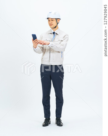 Full-body photo of a middle-aged man wearing work clothes using a smartphone Full-body photo of a middle-aged man wearing work clothes using a smartphone 127929845