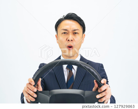 一位中年男性商務人士一邊開車一邊握著方向盤，心情很煩躁 127929863