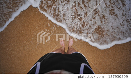 Sea waves washing over tourist's feet standing on Crimean beach Sea waves washing over tourist's feet standing on Crimean beach 127930299