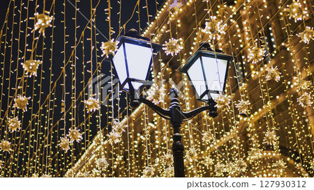 Christmas lights illuminating a street at night 127930312