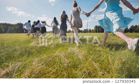 High school students holding hands and running through a field, savoring their summer vacation High school students holding hands and running through a field, savoring their summer vacation 127930345