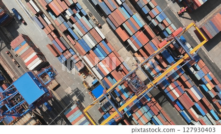 Aerial view of a container terminal with colorful shipping containers and cranes loading and unloading cargo, representing global trade and logistics Aerial view of a container terminal with colorful shipping containers and cranes loading and unloading cargo, representing global trade and logistics 127930403