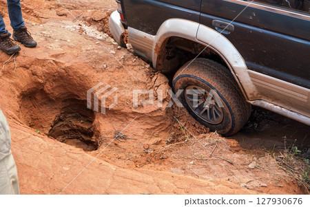 4wd vehicle driving over road with extreme holes and bumps, close up on rear wheel - roads are in very bad conditions in Andringitra, Madagascar, especially after rain 127930676