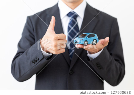 一位身著西裝的中年男性商人拿著模型車豎起大拇指 一位身著西裝的中年男性商人拿著模型車豎起大拇指 127930688