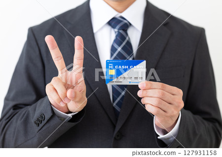 A middle-aged male businessman in a suit holding a bank's IC cash card and holding up two fingers 127931158