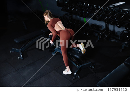 Female athlete lifting dumbbell during workout in gym Female athlete lifting dumbbell during workout in gym 127931310