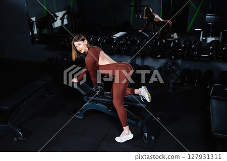 Female athlete lifting dumbbell during workout in gym 127931311