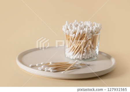 Wooden ecological cotton swab in glass jar on beige background. Wooden ecological cotton swab in glass jar on beige background. 127931565
